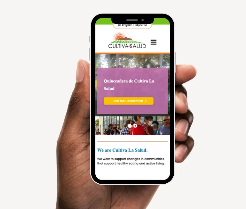 A hand holding a phone, on the phone screen is the Cultiva La Salud website
