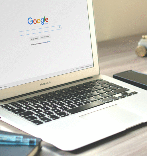 a desk with an open laptop displaying the Google homepage.