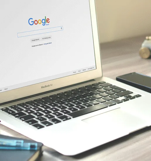 a desk with an open laptop displaying the Google homepage.