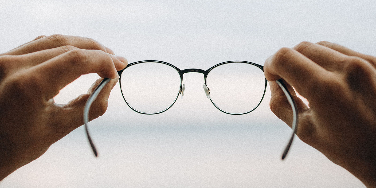 hands holding out a set of eyeglasses
